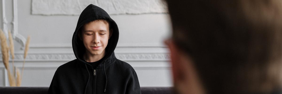 Jongen in een zwarte hoodie die zijn verhaal vertelt aan een consulent