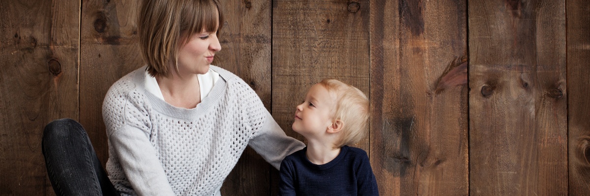 Mama die kijkt naar haar zoontje die terugkijkt. Beiden glimlachend.