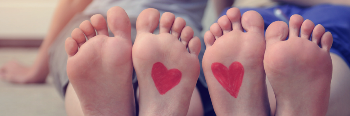 Twee paar voeten waarvan de onderkant gericht zijn naar de camera. Op de twee voeten die het tegen elkaar liggen zijn hartjes getekend.