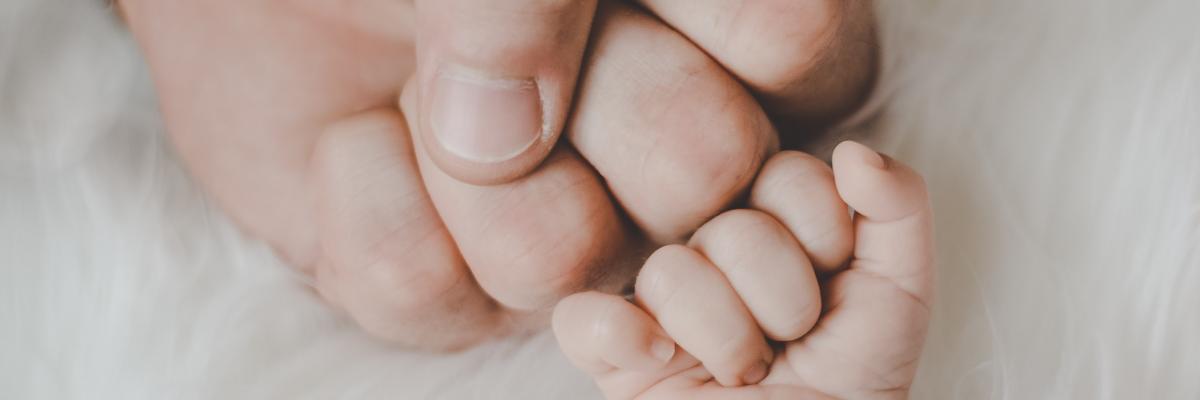 Een mannenhand dat een 'fistbump' doet met een babyhand