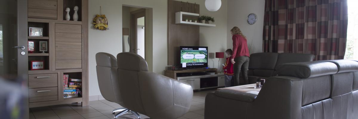 Een leefruimte waar een klein jongtje samen met een jonge vrouw op de Nintendo Wii aan het spelen is.