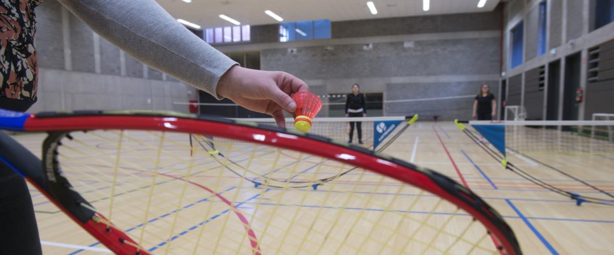 De sportzaal waar enkele meisjes badminton spelen.