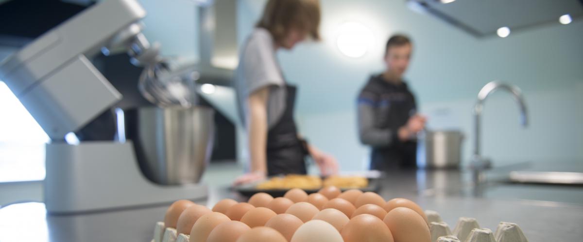 Een doos eieren en een keukenrobot die klaarstaan voor de jongeren die kookles krijgen.