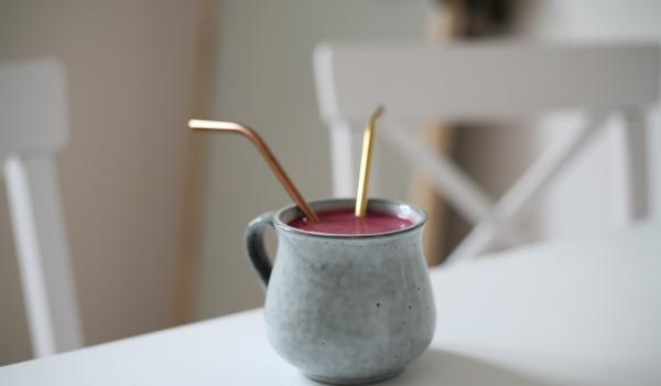 Een oude koffietas, gevuld met Ruby chocolademelk. In de tas steken twee rietjes