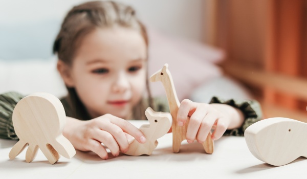 Meisje speelt met houten speelgoeddieren