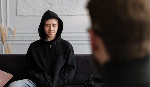 Jongen in een zwarte hoodie die zijn verhaal vertelt aan een consulent