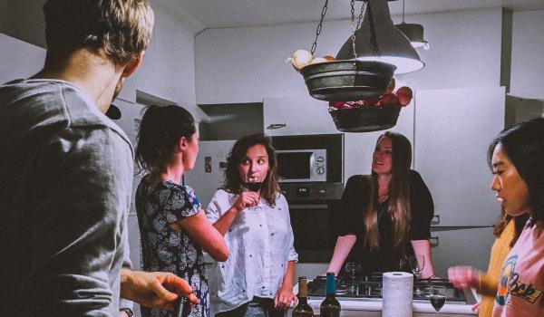 Jonge mensen, staand rond een tafel met eten, gezellig pratend