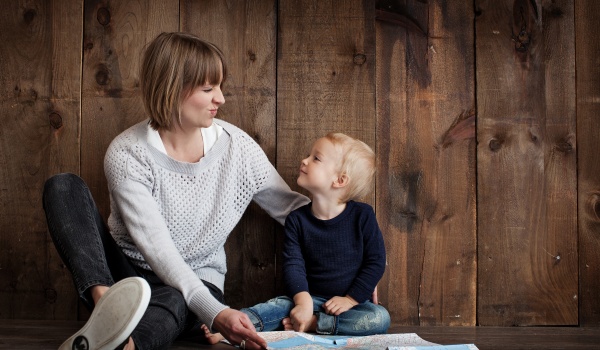 Mama die kijkt naar haar zoontje die terugkijkt. Beiden glimlachend.