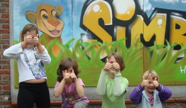 Vier kinderen met opgestoken duim voor het simbahuis.