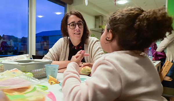 Sylvie Declercq zit aan tafel, etend met een jong meisje