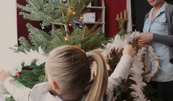 Een jong kind dat haar moeder helpt om de kerstboom te versieren