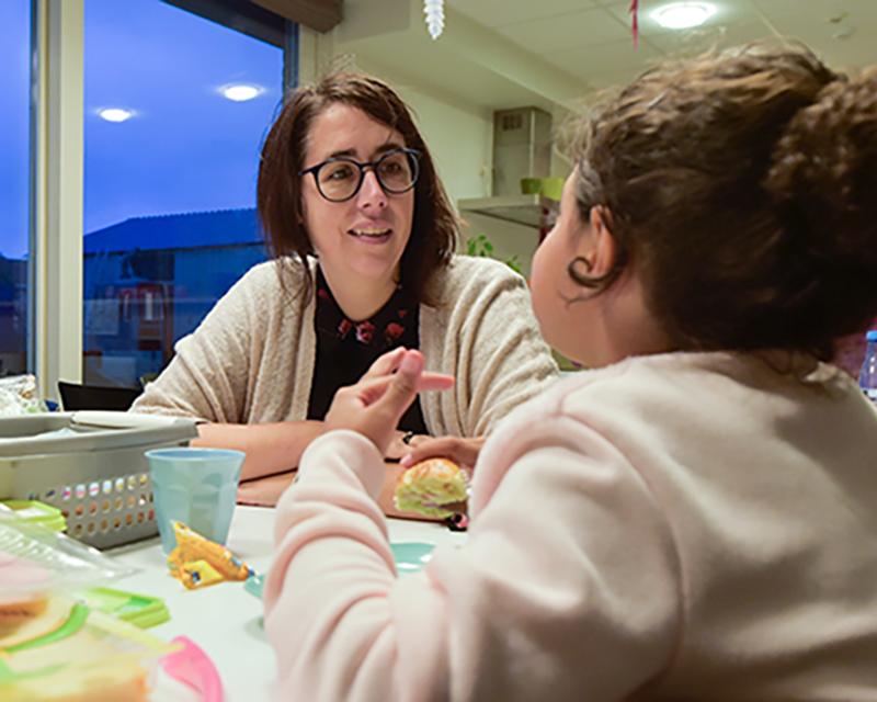 Sylvie Declercq zit aan tafel, etend met een jong meisje