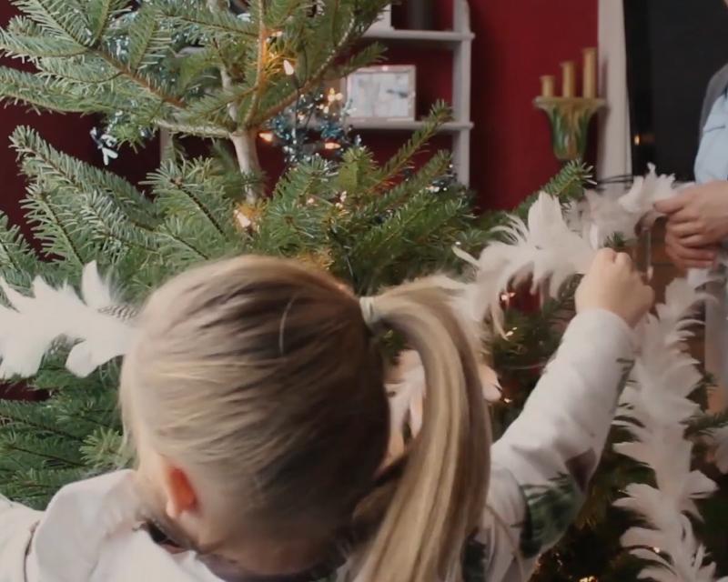 Een jong kind dat haar moeder helpt om de kerstboom te versieren
