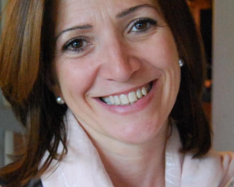 Sarah Van Gysegem, met brede glimlach en een lichtroze sjaal rond haar nek
