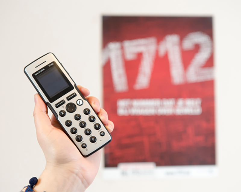 Een hand met een telefoon, voor de poster van 1712