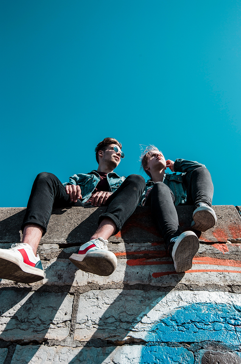 Twee jongeren, zittend op een muurtje