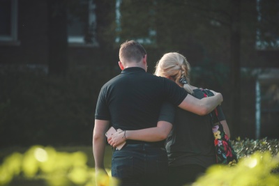 Moeder en zoon lopen arm in arm over straat