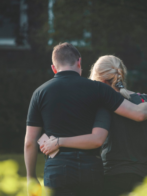 Moeder en zoon lopen arm in arm over straat